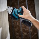A hand uses a blue Makita cordless sander on a wooden surface, producing dust. The scene conveys precision and craftsmanship in woodworking.
