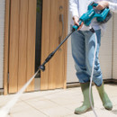 User spraying patio floor with Makita cordless portable pressure washer.