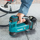 User inflating bicycle tyre with Makita cordless air compressor.