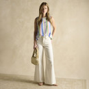Women’s pastel striped sleeveless blouse styled with wide-leg cream trousers and a crossbody bag.