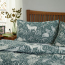 Close-up of green woodland animal duvet cover and pillowcase, detailed deer and hedgehog print with leafy botanical pattern, soft fabric bedding for modern cosy bedroom decor