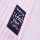 Close-up of branded tag on the shirt  in white and pink on navy fabric.
