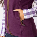 Close-up of hand in zipped pocket on the berry fleece gilet, showing brown trim and embroidered branding.