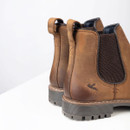 Close-up of the heel and side panel featuring the elastic gusset, pull tabs and embossed bird logo on the leather.