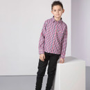 Young boy standing beside a cube wearing a red, white and blue check long-sleeve shirt and black trousers.