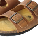 Close-up of brown leather sandal strap with metal buckle detail and cork sole