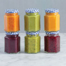 Hexagonal glass Kilner jars filled with colourful sauces and preserves, stacked jars with blue gingham lids, ideal for homemade jams, chutneys and food storage