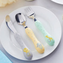 Children’s stainless steel cutlery set with pastel handles on white plate, featuring fork, spoon and knife with animal illustrations and star patterns