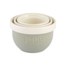 Nested ceramic measuring cups in pastel green with cream rims, embossed “1 CUP” marking, stackable baking measuring set isolated on white background
