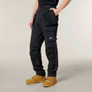 Black Hard Yakka work trousers with multiple utility pockets, reinforced knee panels, and tan work boots.