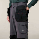 Close-up of grey work trousers showing large tool pocket and Hard Yakka branding on cargo pocket.