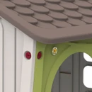 Close-up of play house roof corner with textured brown tiles and decorative fixings on green wall