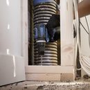 Close-up of DXPULSE drill driving a screw into timber stud beside flexible conduit piping, showcasing precision drilling in home renovation or electrical installation.