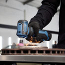 Close-up of a right-angle cordless tool in use grinding metal, with visible sparks and gloved hand for safety.