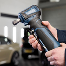 Hand holding a blue and black DXPULSE right-angle power tool, highlighting the compact head and comfortable grip in a garage setting.