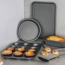 Baking set in use with muffins in the tray, loaf cake in the tin, and cookies on a work surface.