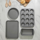 Top-down view of baking set arranged on a marble surface with wooden spoons and bread rolls nearby.
