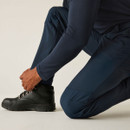 Detail of blue performance trousers worn while kneeling, highlighting reinforced knee and durable material