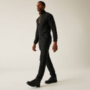 Male model wearing black performance trousers and quarter-zip top, walking in outdoor footwear