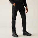 Men’s black technical trousers front view with zip pockets and articulated knees, styled with hiking boots