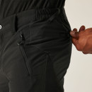 Detail of black hiking trousers with reinforced knees, worn while tying sturdy walking boots
