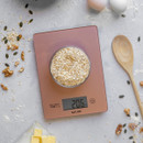 Top view of oats in a bowl on the scale with ingredients and utensils arranged around it.