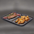 Divided baking tray holding cooked steak with onions on the ridged side and roasted potato wedges on the perforated side.