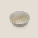 Cream stoneware bowl with scalloped rim, top angled view.