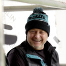 Person wearing a black and teal Makita bobble hat with pom-pom, smiling on a construction site