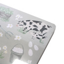 Close-up of placemat corner showing illustrated cow and calf, eggs and a bucket.