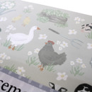 Close-up of placemat design with a goose, hen, chicks and garden fork among flowers.