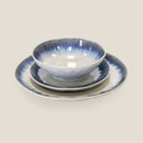 Stacked ceramic tableware set including bowl and plates with blue rim detailing.