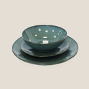 Green stoneware bowl placed on a matching plate and larger dinner plate, forming a coordinated tableware set.