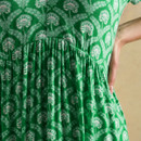 Detail of gathered waist seam on green patterned dress showing lightweight material