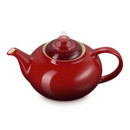 Close-up side view of red glazed teapot with curved spout and handle