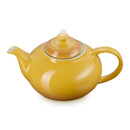 Close-up side view of yellow glazed teapot with curved spout and handle
