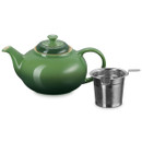 Green ceramic teapot with lid and removable stainless steel infuser on a plain background