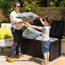 Woman and child placing cushions into a black plastic garden storage box with open hinged lid