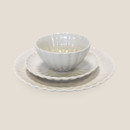 White stoneware bowl placed on matching scalloped side plate and dinner plate, shown at an angled front view on a light background.