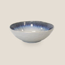 Blue and white glazed stoneware bowl with textured exterior and reactive glaze finish on a light background.