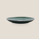 Green glazed stoneware side plate shown from the side on a light background.
