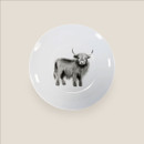 White porcelain side plate with Highland cow illustration viewed from above on a light background.