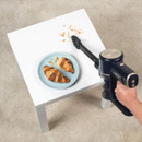 Handheld Beldray AiroEase vacuum cleaning crumbs from a coffee table, ideal for quick spot cleaning around the home.