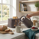 Salter Malmo brown kettle pouring hot water into a mug on a kitchen worktop, with matching toaster and breakfast items nearby.