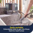 Portable Beldray spot cleaner with extended hose cleaning carpeted stairs and hard-to-reach areas around the home.
