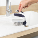 Beldray Scrape and Scrub cleaning brush being used to clean a kitchen sink, featuring an integrated detail brush for hard-to-reach areas.