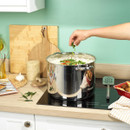 Large stainless steel stockpot with glass lid simmering on a hob, featuring sturdy side handles and polished finish.
