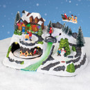 Light-up Christmas village decoration featuring a snowy house with multicoloured LED lights, moving Santa sleigh, glowing waterfall effect, snow-covered trees and festive winter figures.