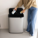 Brabantia Bo Touch Bin 60L in Mineral Concrete Grey with lid open while recyclable packaging is placed inside the dual-compartment interior.