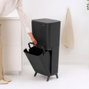 Person removing the lower inner bucket from a Brabantia SortUp dual recycling bin for easy emptying and cleaning.